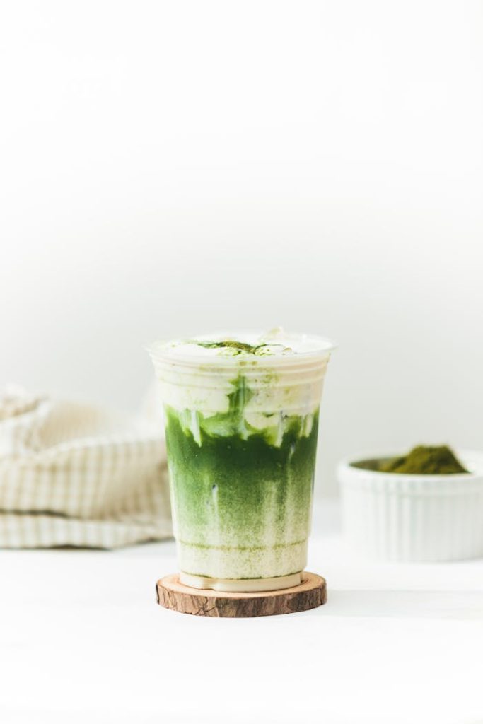 Close-up of a layered matcha latte in a clear cup, perfect for promoting health and wellness.